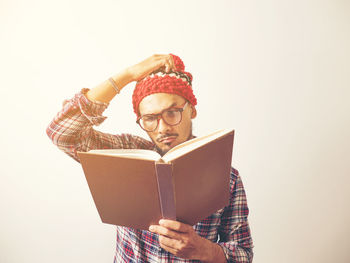 Young man holding book against white background