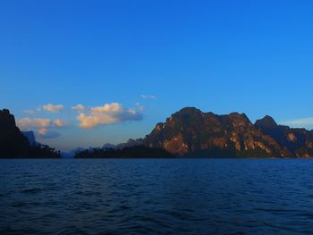 Scenic view of sea by mountain against sky