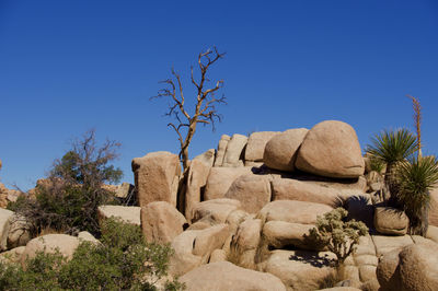 Rocks on landscape against clear blue sky