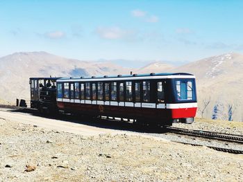 Train on railroad track by mountain against sky