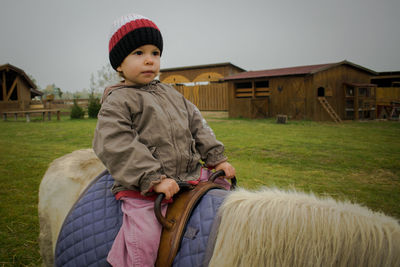 Cute boy with horse on field against sky