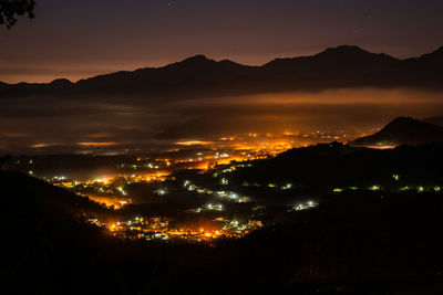 Illuminated cityscape against sky at night