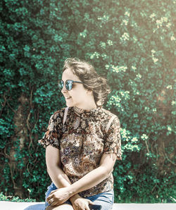 Woman looking away while standing by tree in forest