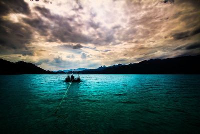 Silhouette of boats in sea against cloudy sky