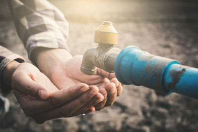 Cropped image of woman with hands cupped under faucet