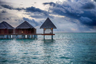 Pier on sea against cloudy sky