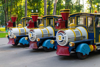 Multi colored toy trains parked on road in city