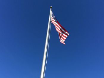 Low angle view of flag against clear blue sky