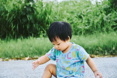 Full length of cute boy playing while siting on road