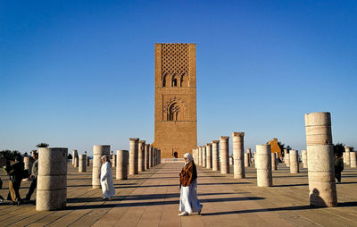 Rear view of people walking against clear blue sky