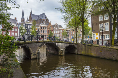 Bridge over river by buildings in city