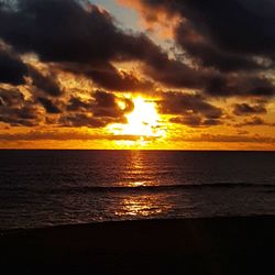 Scenic view of sea against dramatic sky during sunset