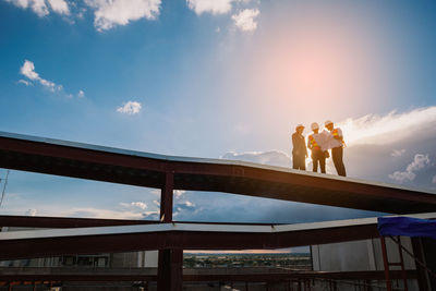 Low angle view of people standing against sky