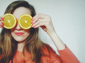 Young woman holding orange slices against white background