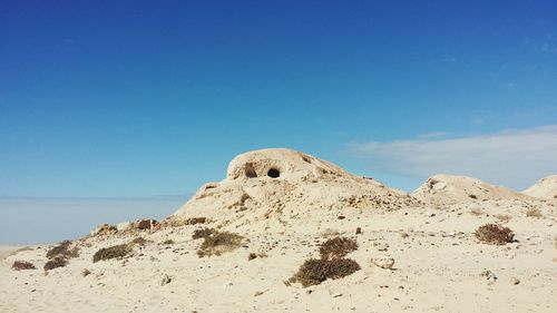 Low angle view of sand against blue sky