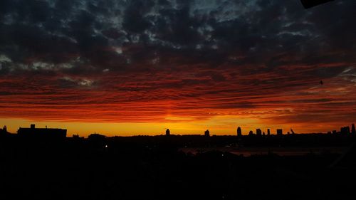 Silhouette buildings against dramatic sky during sunset