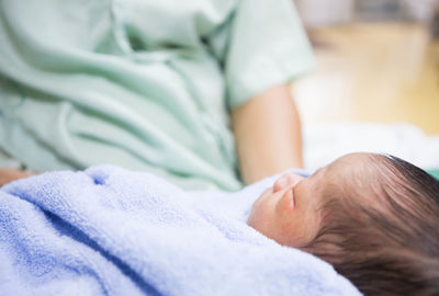 Midsection of woman holding baby wrapped in blanket