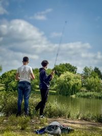 Rear view of man standing by lake against sky