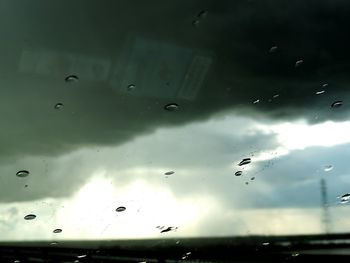 Low angle view of sky seen through wet glass window