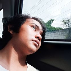 Portrait of young woman looking through window