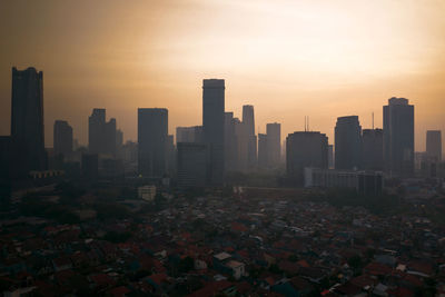 Modern buildings in city against sky during sunset