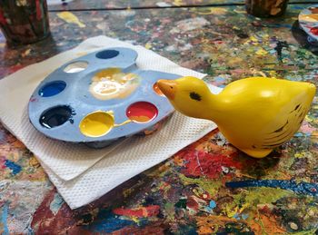 High angle view of rubber duck with palette and tissue paper on table