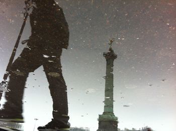 Upside down image of person and berlin victory column reflecting in puddle