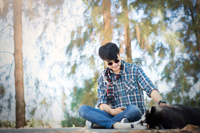 Young man sitting by dog