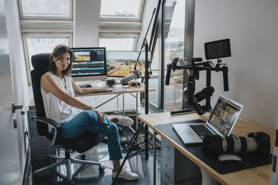 Photographer sitting on chair by desktop pc in studio