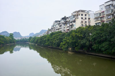 Lake amidst trees and buildings against sky