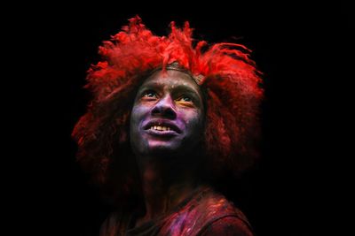 Close-up of man with painted face looking away against black background