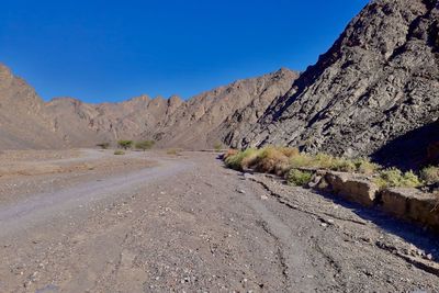 Scenic view of road amidst mountains against clear blue sky