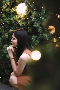 Side view of woman close her eyes under christmas trees 