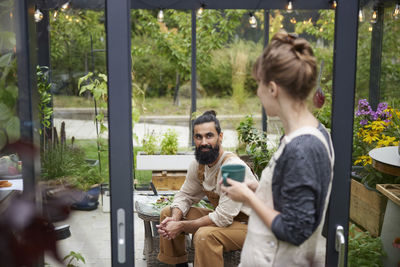 Side view of couple sitting on window