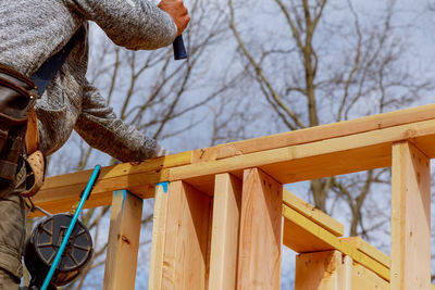 Low angle view of man holding rope against trees