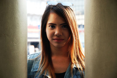 Portrait of young woman standing by columns