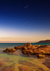 Star trails over sea during sunset