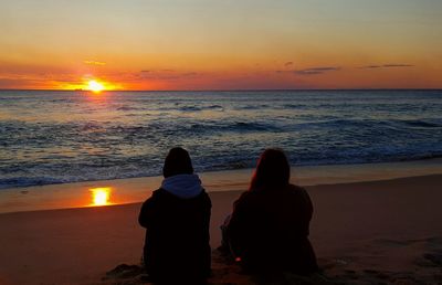 Rear view of women on beach during sunset