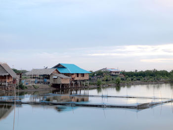 Houses by lake and buildings against sky