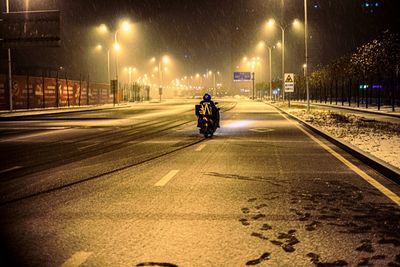 Man riding motorcycle on road at night