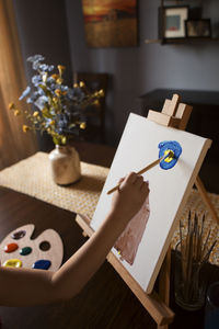 Cropped hand of girl painting on canvas at home