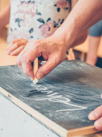 Cropped hand writing on slate with chalk