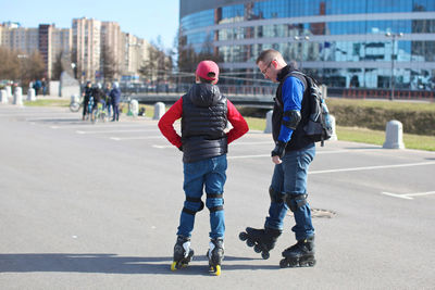 Father and son inline skating at parking lot in city