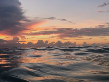 Scenic view of sea against dramatic sky during sunset