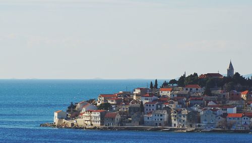 Buildings by sea against clear sky