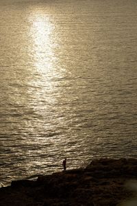 Silhouette person standing on beach against sky during sunset