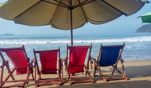 Chairs on beach by sea against sky