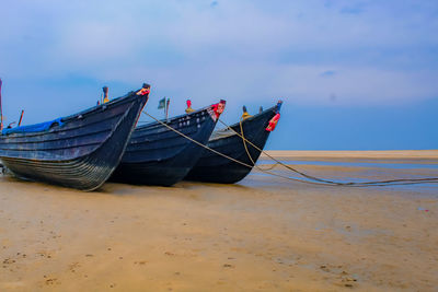 Boat moored on beach against sky