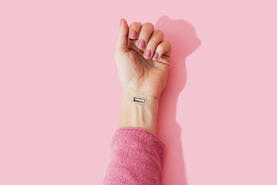 Close-up of woman hand over pink background