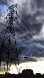 Low angle view of electricity pylon against cloudy sky